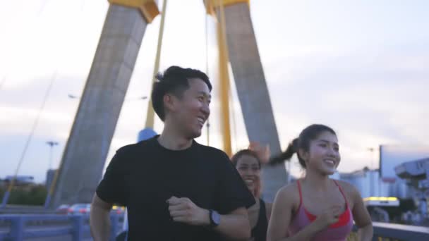 Junge Sportlerinnen und Sportler an der Brücke reden und gehen — Stockvideo