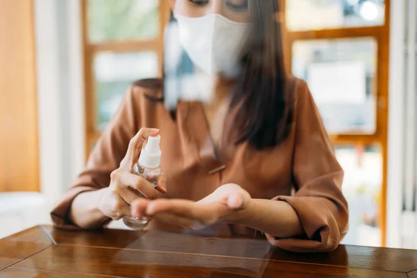 Mulher usando máscara usando desinfetante no café — Fotografia de Stock