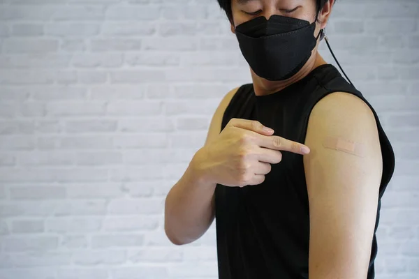 Hombre joven vacunado que muestra brazos con vendaje adhesivo de yeso después de recibir la inyección de la vacuna Covid-19 — Foto de Stock