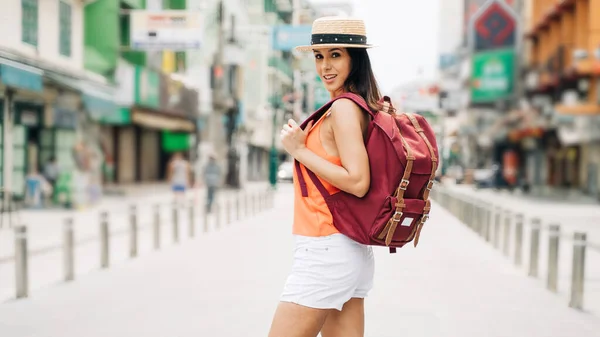 幸せと興奮ヒスパニック系の女の子旅行者着用夏服で帽子とバックパックバッグでアジア. — ストック写真