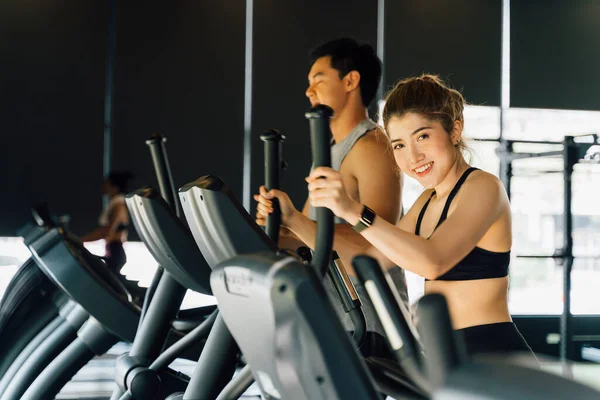 Atractiva mujer asiática fitness usando entrenador elíptico en el gimnasio y mirando a la cámara. Estilo de vida saludable y pérdida de peso — Foto de Stock