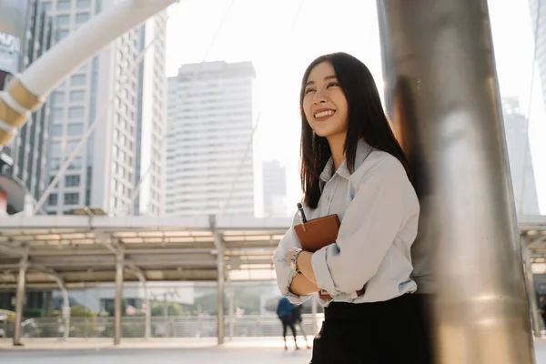 Mujer de negocios sonriente de pie con libro y pluma — Foto de Stock