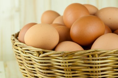 Ahşap arka planda bir hasır sepet yumurta dolu koymak