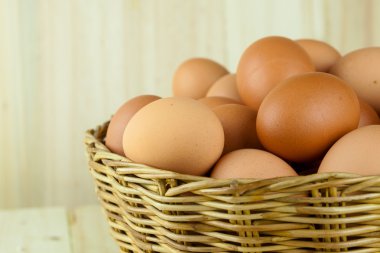Ahşap arka planda bir hasır sepet yumurta dolu koymak