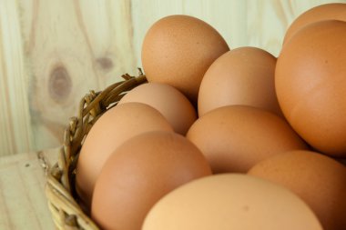 Ahşap arka planda bir hasır sepet yumurta dolu koymak