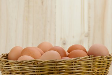 Ahşap arka planda bir hasır sepet yumurta dolu koymak