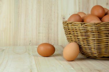 Ahşap arka planda bir hasır sepet yumurta dolu koymak