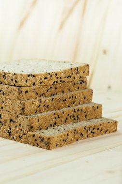 Taze dilim kepekli ekmek ile çeşitli tohum ve tahıllı ahşap arka plan siyah plaka üzerinde