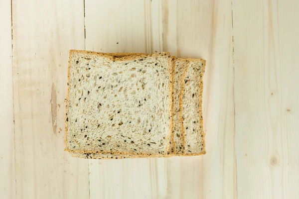 Fresh slices of wholewheat bread with various seeds and multigrain on the black plate in wood background — Stock Photo, Image