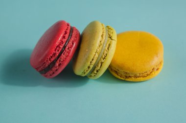 Set of colorful macaroons sitting next to each other in blue turquoise pastel isolated background