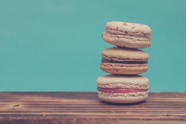 Stack of colorful macarons stacked up like a tower in blue turquoise pastel isolated background on the wood table.