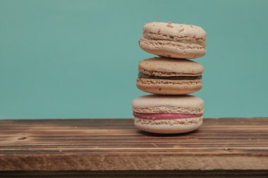 Stack of colorful macarons stacked up like a tower in blue turquoise pastel isolated background on the wood table.