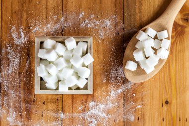 Havadan görünümü, kesme şeker kare şeklinde kase ve ham şeker kaşıkla ahşap arka planda üzerine dökmek