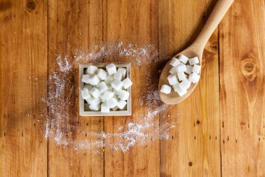 Havadan görünümü, kesme şeker kare şeklinde kase ve ham şeker kaşıkla ahşap arka planda üzerine dökmek