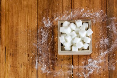 Havadan görünümü şeker küpleri kare şeklinde kaseyle ham şeker ahşap arka planda üzerine dökmek