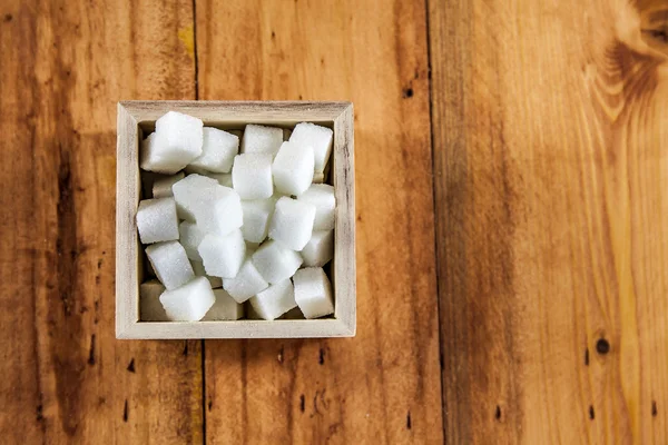 Aerial View of Sugar Cubes in Square Shaped Bowl with Unrefined Sugar spill over in Wooden Background — Stock Photo, Image