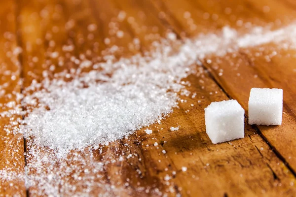 Derrame de azúcar blanco granulado sobre fondo de madera — Foto de Stock