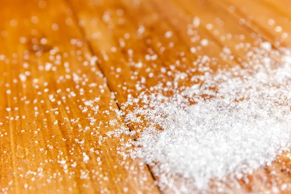 Derrame de azúcar blanco granulado sobre fondo de madera — Foto de Stock