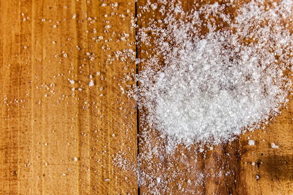 Derrame de azúcar blanco granulado sobre fondo de madera — Foto de Stock