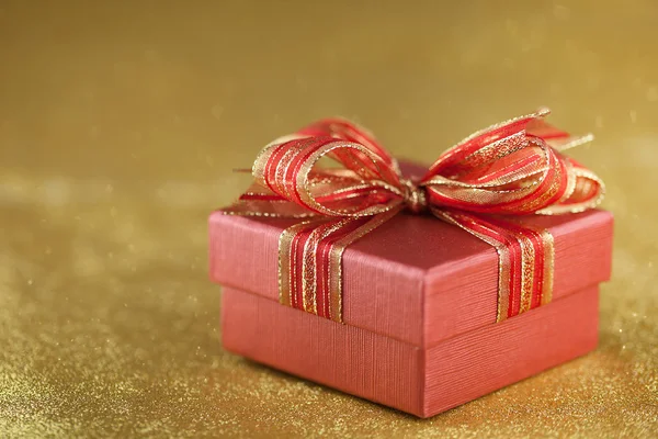 Красный подарочный бокс на золотом фоне блесток — стоковое фото