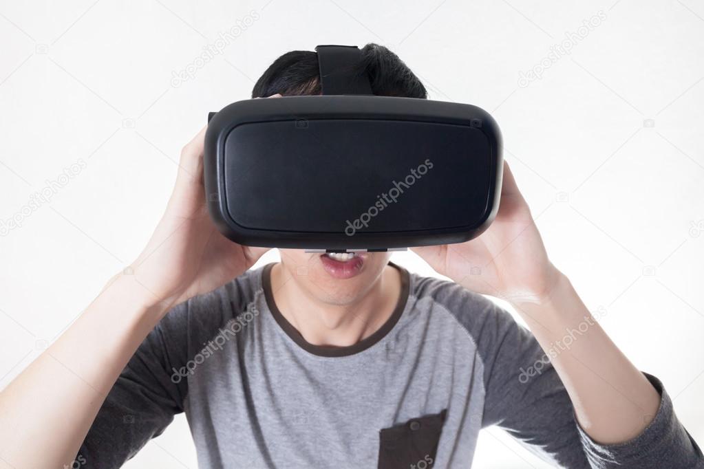 Asian man wearing VR goggle and immersing himself in VR multimedia in white isolated.