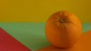 Olgun bir turuncu, sarı bir arkaplanda izole edilmiş, yeşil bir zemin üzerinde, kırmızı bir zemin üzerinde, birleşik bir zemin üzerinde