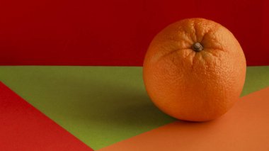 Olgun bir turuncu, sarı bir arkaplanda izole edilmiş, yeşil bir zemin üzerinde, kırmızı bir zemin üzerinde, birleşik bir zemin üzerinde