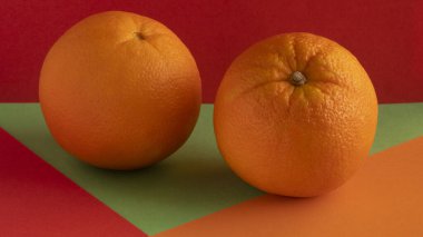 Olgun bir turuncu, sarı bir arkaplanda izole edilmiş, yeşil bir zemin üzerinde, kırmızı bir zemin üzerinde, birleşik bir zemin üzerinde