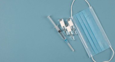 COVID-19 'un şırıngası ve aşısı ve maskesi koruyucu. Sağlık ve tıbbi konsept.