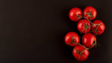 Siyah arka planda baharatlı taze kiraz domatesleri. Kopyalama alanı olan üst görünüm.