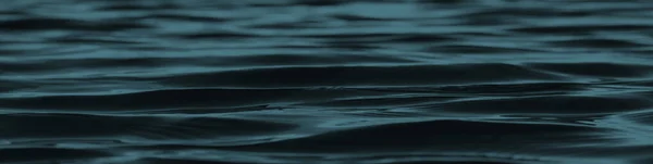 Koyu mavi soyut arka plan. Işığın yansıması suyun pürüzsüz yüzeyinde küçük dalgalarla. Tasarım için kopyalama alanı olan Tidewater yeşili arkaplan. Web pankartı.