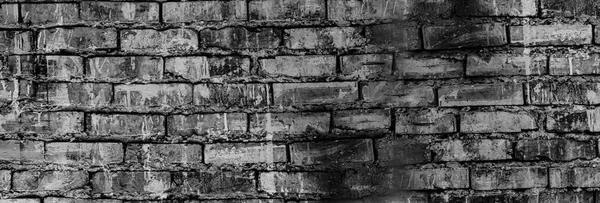 Black grunge background. Black old brick wall. Dark gray stone wall. Collapsing brickwork. Weathered stone wall.