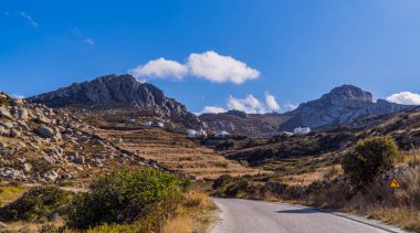 Yunanistan 'ın Tinos, Cyclades adasındaki Mount Exomvourgo eteklerindeki yol ve kayalık manzaraların panoramik manzarası