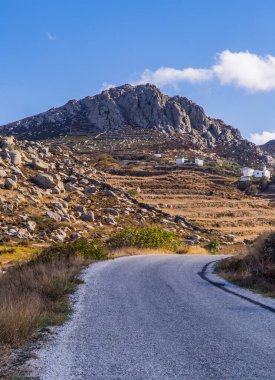 Yunanistan 'ın Tinos, Cyclades adasındaki Mount Exomvourgo eteklerindeki yol ve kayalık manzaralar dikey görünüm
