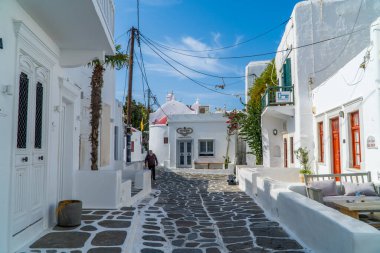 Mykonos Town (Chora), Greece - October 18, 2020 - street shot of an elderly man walking with traditional Cycladic houses in Mykonos Town, Cyclades clipart