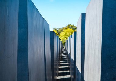 Berlin, Almanya - 3 Eylül 2019 - Soykırım Anıtı 'nın içinde mavi gökyüzü ve arka planda bina olan kaldırım