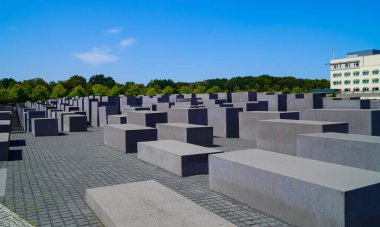 Berlin, Almanya - 2 Eylül 2019 - Soykırım anıtı, sonbahar güneşinde, arka planda ağaçlar olan beton bloklar