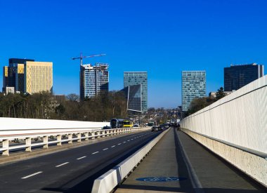 Kirchberg, Lüksemburg - 13 Şubat 2020 - tramvay ve araçlar Kızıl Köprü 'de ilerlerken Kirchberg iş alanı ufuk çizgisini sağ tarafta bisiklet yolu ile görüyorlar.