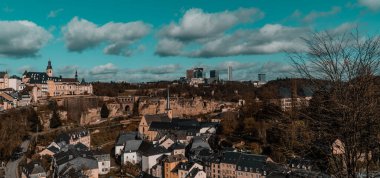 Panorama manzaralı Lüksemburg - kiliseleri, ortaçağ evleri ve Kirchberg iş bölgesi gökdelenleri arkada mavi gökyüzü ve dramatik bulutlar