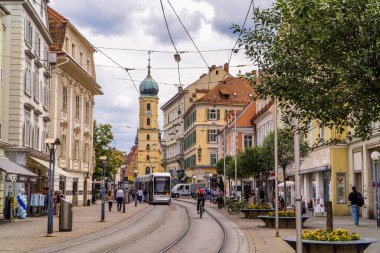 Graz, Avusturya - 16 Haziran 2020 - Graz, Styria 'daki geleneksel Avusturya evlerinin önündeki yaya bölgesinde modern tramvay ve bisikletçi