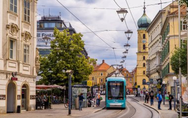 Graz, Avusturya - 16 Haziran 2020 - Graz 'da modern tramvay sokak arabası, insanlar ve geleneksel Avusturya binaları ile panoramik sokak sahnesi