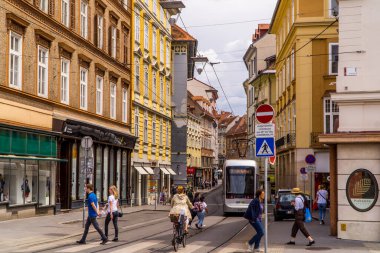 Graz, Avusturya - 16 Haziran 2020 - Geleneksel Avusturya evlerinin önündeki modern tramvay sokağının yanındaki yolcular