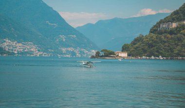 Como, İtalya - 12 Ağustos 2020 - Arkasında dağlar ve kasabalar olan Lombardiya 'nın Como Gölü' nde yüzen panoramik su uçağı görüntüleri