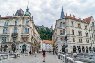 Ljubljana, Slovenya - 26 Haziran 2020 - Ljubljanica nehri üzerindeki köprüde insanlar ve arkada Ljubljana Kalesi