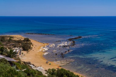 İtalya 'nın Sicilya kentindeki Scala dei Turchi' de bitkilerle ve mavi denizin farklı tonlarıyla kumsallardaki insanların panoramik görüntüsü