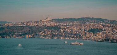 İstanbul, Türkiye - 2 Şubat 2021 - İstanbul Boğazı 'ndaki feribotların panoramik hava günbatımı manzarası, Asya tarafında Uskudar bölgesi ve tepedeki İstanbul Büyük Camlica Camii.