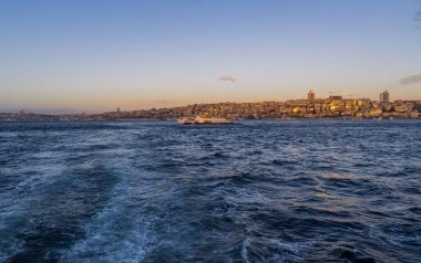İstanbul, Türkiye - 9 Şubat 2021 - İstanbul Boğazı 'ndaki feribotun güzel panoramik manzarası ve gündoğumunda Avrupa tarafında Galata bölgesinin ufuk çizgisi