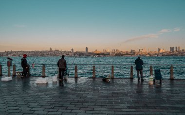 İstanbul, Türkiye - 9 Şubat 2021 - İstanbul 'un Asya yakasındaki Uskudar rıhtımında gün doğumunda balıkçılar