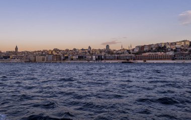 İstanbul, Türkiye - 9 Şubat 2021 - Avrupa tarafındaki Tophane ve Galata bölgelerinin camileri, liman şantiyesi, binaları ve güneş doğarken Galata Kulesi 'nin güzel panoramik manzarası
