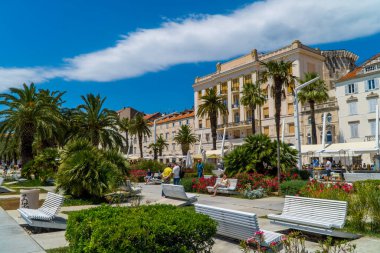 Ayrıl, Hırvatistan - 10 Temmuz 2020 - Split Gezinti Alanı 'nda geleneksel mimarinin önündeki bank ve insanlar